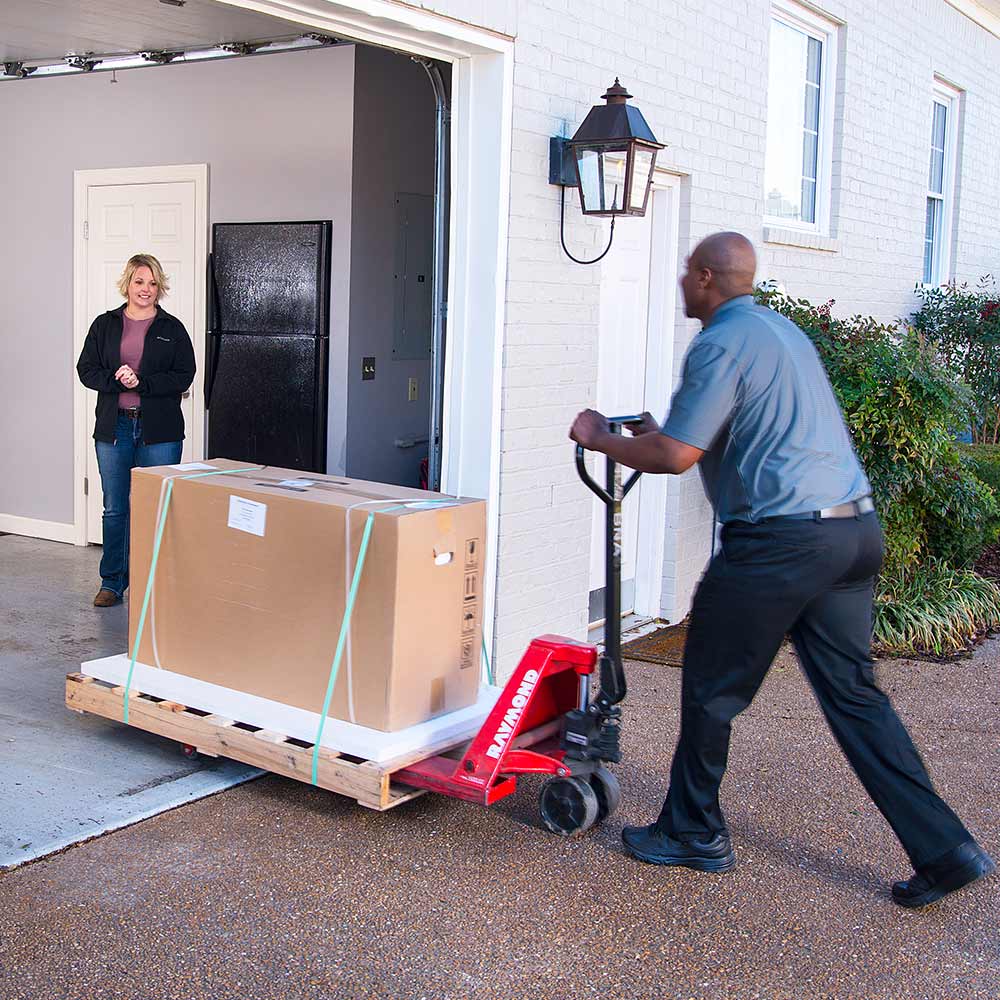 Delivery of a pallet of natural stone panels via LTL service with driver positioning pallet in customer's garage using pallet jack